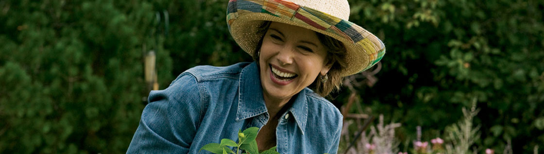 Kvinna i trädgård ler